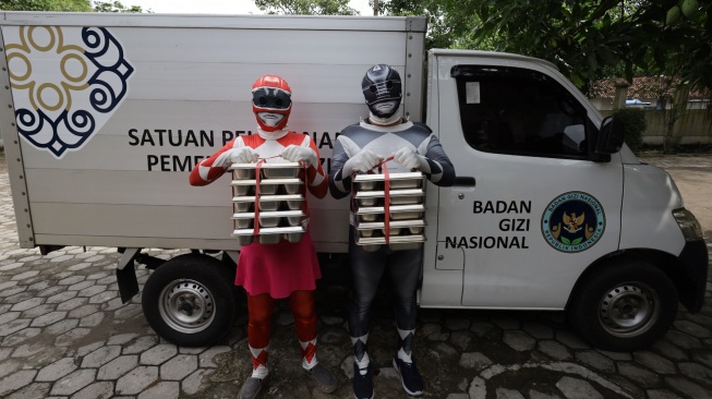 Dua petugas berkostum Power Rangers mengantar Makan Bergizi Gratis (MBG) di SD Negeri Tempurejo 1, Kota Kediri, Jawa Timur, Kamis (13/11/2025). [ANTARA FOTO/Prasetia Fauzani/bar]