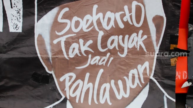 Poster tolak Soeharto menjadi pahlawan saat mengikuti Aksi Kamisan ke-886 di depan Istana Merdeka, Jakarta, Kamis (13/11/2025). [Suara.com/Alfian Winanto]