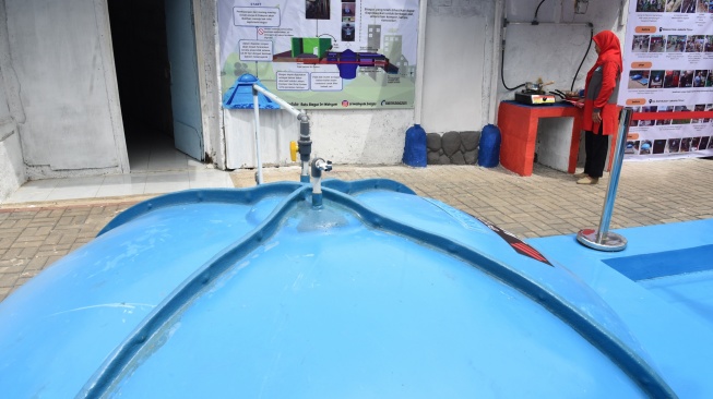 Warga memasak menggunakan kompor biogas saat peresmian pemanfaatan biogas melalui instalasi tangki septik komunal oleh Gubernur DKI Jakarta Pramono Anung di permukiman Gang Delta, Pekayon, Pasar Rebo, Jakarta Timur, Kamis (13/11/2025). [ANTARA FOTO/Indrianto Eko Suwarso/bar]