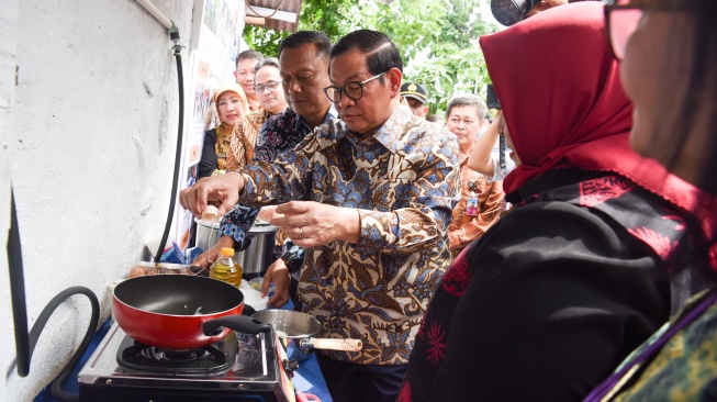 Gubernur DKI Jakarta Pramono Anung (tengah) memasak telur menggunakan kompor biogas saat meresmikan pemanfaatan biogas melalui instalasi tangki septik komunal di permukiman Gang Delta, Pekayon, Pasar Rebo, Jakarta Timur, Kamis (13/11/2025). [ANTARA FOTO/Indrianto Eko Suwarso/bar]