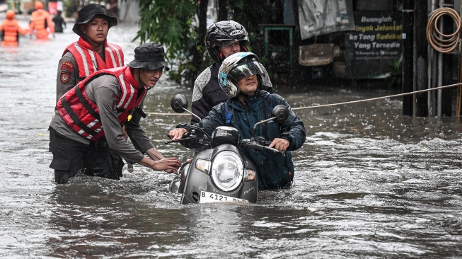Personel polisi membantu warga mengevakuasi sepeda motor saat banjir di Komplek Polri Pondok Karya, Mampang Prapatan, Jakarta, Selasa (18/11/2025). [ANTARA FOTO/Sulthony Hasanuddin/nym]