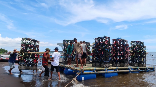 Nelayan mengangkut apartemen ikan yang akan ditenggelamkan di laut Pantai Bimorejo, Bajulmati, Banyuwangi, Jawa Timur, Selasa (18/11/2025). [ANTARA FOTO/Budi Candra Setya/YU]