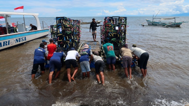 Nelayan mengangkut apartemen ikan yang akan ditenggelamkan di laut Pantai Bimorejo, Bajulmati, Banyuwangi, Jawa Timur, Selasa (18/11/2025). [ANTARA FOTO/Budi Candra Setya/YU]