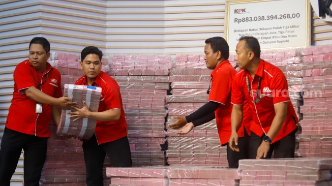 Petugas menyusun tumpukan aset hasil rampasan senilai kurang lebih Rp 883 miliar (ditampilkan Rp 300 miliar) diserahkan KPK kepada PT. Taspen (Persero) di Gedung Merah Putih KPK, Jakarta, Kamis (20/11/2025). [Suara.com/Alfian Winanto]