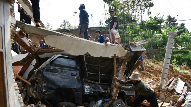 Sejumlah warga menyingkirkan reruntuhan tembok dan material longsor yang menimpa mobil di Desa Wagir Kidul, Pulung, Ponorogo, Jawa Timur, Kamis (20/11/2025). [ANTARA FOTO/Siswowidodo/nz]