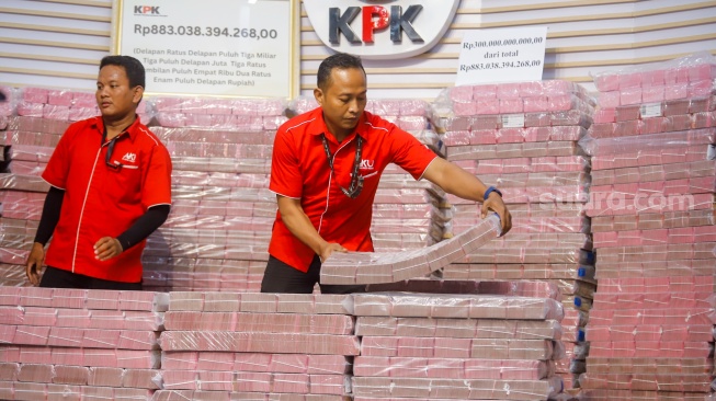 Petugas menyusun tumpukan aset hasil rampasan senilai kurang lebih Rp 883 miliar (ditampilkan Rp 300 miliar) diserahkan KPK kepada PT. Taspen (Persero) di Gedung Merah Putih KPK, Jakarta, Kamis (20/11/2025). [Suara.com/Alfian Winanto]