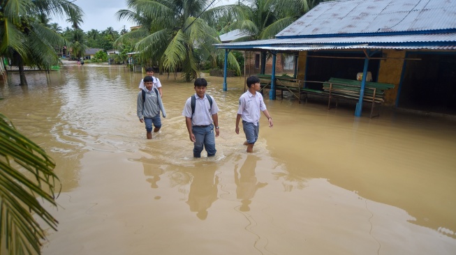 Sejumlah pelajar melintasi banjir yang merendam Nagari Kampuang Galapuang, Ulakan Tapakis, Padang Pariaman, Sumatera Barat, Selasa (25/11/2025). [ANTARA FOTO/Iggoy el Fitra/bar]