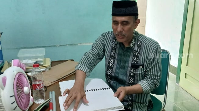 Rasino, guru tuna netra di SMKN 8 Solo saat menyiapkan materi untuk mengajar. (Suara.com/Ari Welianto),