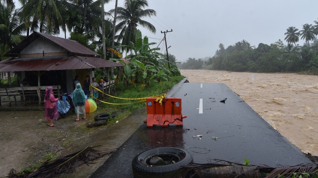 Warga berada di tepi jalan penghubung antar desa yang longsor akibat luapan sungai di Nagari Salibutan, Lubuk Alung, Padang Pariaman, Sumatera Barat, Selasa (25/11/2025). [ANTARA FOTO/Iggoy el Fitra/bar]
