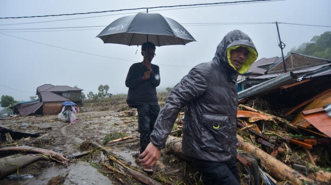 Warga melintasi material longsor di Toboh Tangah, Nagari Malalak Timur, Agam, Sumatera Barat, Kamis (27/11/2025). [ANTARA FOTO/Iggoy el Fitra/YU]