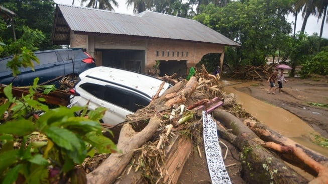 Warga melihat dua unit mobil yang terseret banjir bandang di Lubuk Minturun, Padang, Sumatera Barat, Kamis (27/11/2025). [ANTARA FOTO/Iggoy el Fitra/foc]