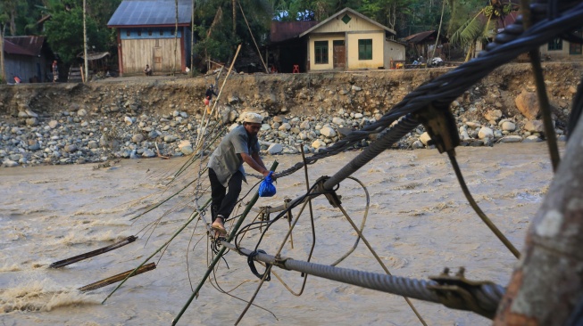 Sejumlah warga melintasi jembatan alternatif yang menghubungkan Desa Blang Meurandeh dan Desa Blang Puuk Beutong Ateuh Banggalang, Nagan Raya, Aceh, Minggu (30/11/2025). [ANTARA FOTO/Syifa Yulinnas/nz]