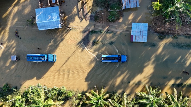Foto udara Sejumlah kendaraan melintasi genangan banjir yang merendam jalan lintas nasional Banda Aceh-Medan di Desa Ladang Rimba, Trumon Tengah, Aceh Selatan, Aceh, Senin (1/12/2025). [ANTARA FOTO/Syifa Yulinnas/YU]