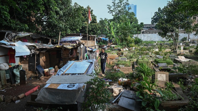 Warga berjalan di depan rumahnya di kawasan Tempat Pemakaman Umum (TPU) Menteng Pulo II, Jakarta, Selasa (2/12/2025). [ANTARA FOTO/Fauzan/foc]
