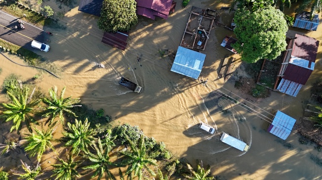 Foto udara Sejumlah kendaraan melintasi genangan banjir yang merendam jalan lintas nasional Banda Aceh-Medan di Desa Ladang Rimba, Trumon Tengah, Aceh Selatan, Aceh, Senin (1/12/2025). [ANTARA FOTO/Syifa Yulinnas/YU]