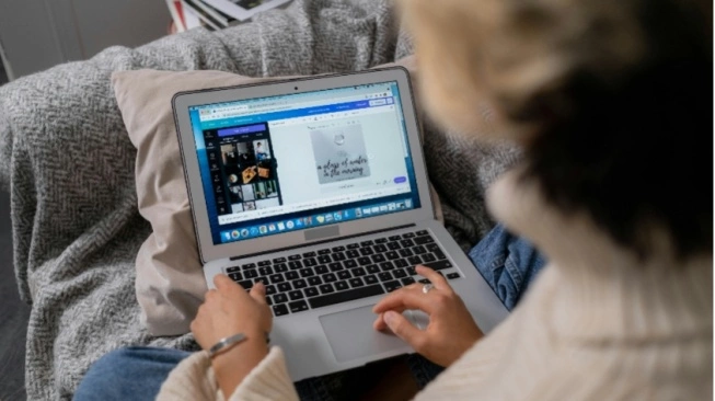 Seseorang sedang mengedit slide presentasi di Canva lewat laptop untuk diexport ke format yang tepat sesuai kebutuhan media sosial atau cetak