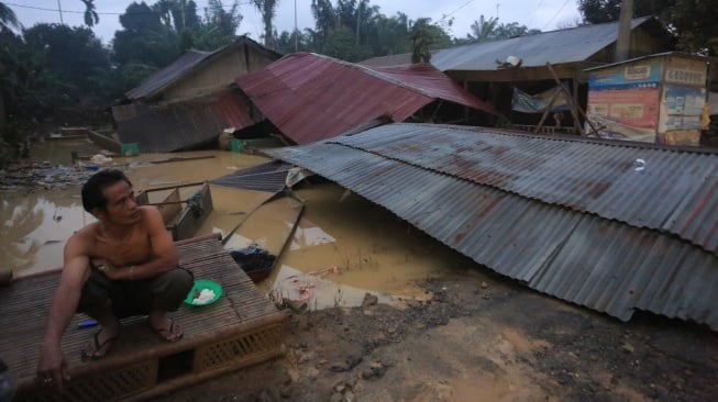 Seorang warga korban banjir berada di samping rumahnya yang hancur setelah diterjang banjir bandang di Desa Sungai Liput, Kecamatan Kejuruan, Aceh Tamiang, Aceh, Selasa (2/12/2025). [ANTARA FOTO/Syifa Yulinnas/bar]