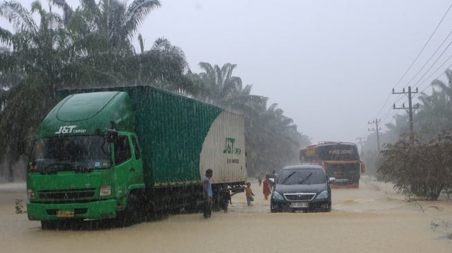 Sejumlah kendaraan melintasi jalan lintas Nasional Medan-Banda Aceh yang terendam banjir di Desa Sungai Liput, Kecamatan Kejuruan, Aceh Tamiang, Aceh, Selasa (2/12/2025). [ANTARA FOTO/Syifa Yulinnas/bar]