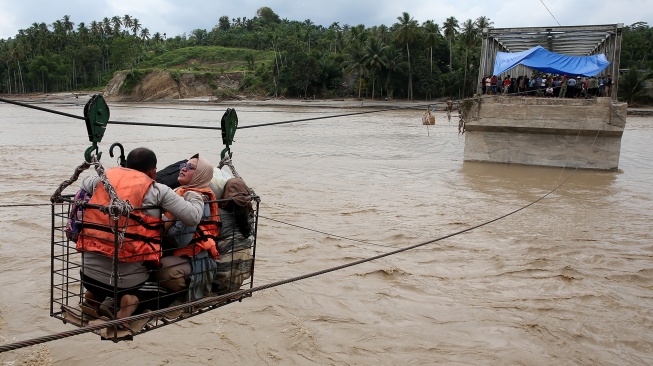 Warga menggunakan kabel baja yang untuk menyeberangi Sungai Juli pascaputusnya Jembatan Juli di jalan lintas Bireuen - Takengon, Aceh, Selasa (2/12/2025). [ANTARA FOTO/Irwansyah Putra/bar]