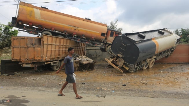 Seorang warga melintas di dekat truk tangki yang terbawa arus banjir di Desa Bukit Rata, Kejuruan muda, Kabupaten Aceh Tamiang, Aceh, Rabu (3/12/2025). [ANTARA FOTO/Syifa Yulinnas/nz]