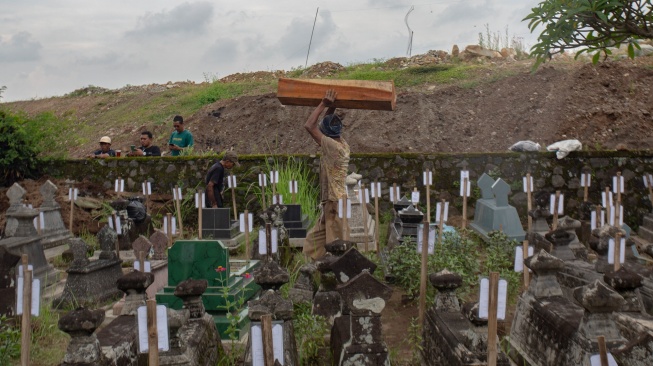 Pekerja membawa peti kayu saat proses relokasi makam di Padukuhan Kaweden, Tirtoadi, Mlati, Sleman, D.I Yogyakarta, Rabu (3/12/2025). [ANTARA FOTO/Andreas Fitri Atmoko/nym]