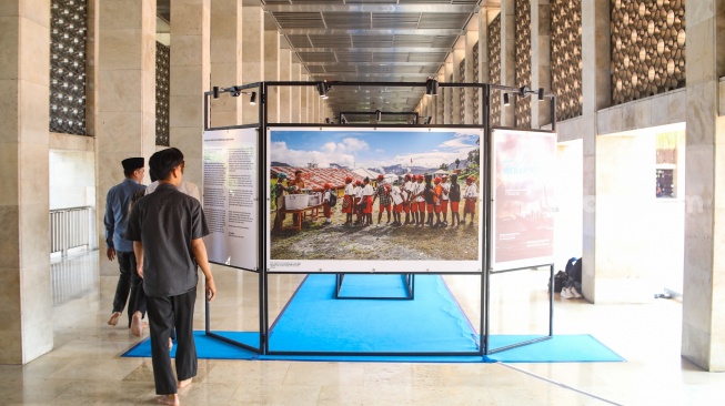 Pengunjung mengamati sejumlah karya yang ditampilkan pada pameran Haluan Merah Putih di selasar Al Fattah, Masjid Istiqlal, Jakarta, Jumat (5/12/2025). [Suara.com/Alfian Winanto]