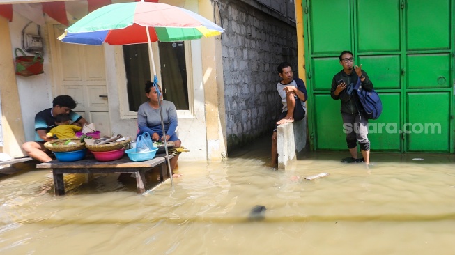 Warga beraktivitas saat banjir rob di Muara Angke, Jakarta, Jumat (5/12/2025). [Suara.com/Alfian Winanto]