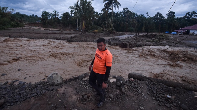 Seorang relawan berdiri di tepi Sungai Nanggang yang meninggi di kawasan permukiman bekas terdampak banjir bandang di Jorong Kayu Pasak, Nagari Salareh Aia, Palembayan, Agam, Sumatera Barat, Sabtu (6/12/2025). [ANTARA FOTO/Wahdi Septiawan/foc]
