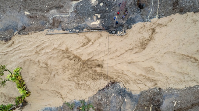 Foto udara warga menyaksikan Sungai Nanggang yang meninggi di kawasan permukiman bekas terdampak banjir bandang di Jorong Kayu Pasak, Nagari Salareh Aia, Palembayan, Agam, Sumatera Barat, Sabtu (6/12/2025). [ANTARA FOTO/Wahdi Septiawan/foc]
