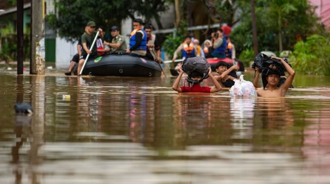 Sejumlah pelajar membawa tas untuk melintasi banjir di Baleendah, Kabupaten Bandung, Jawa Barat, Sabtu (6/12/2025). [ANTARA FOTO/Novrian Arbi/foc]