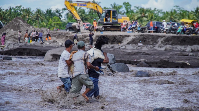 Warga melintasi banjir lahar hujan Gunung Semeru untuk mengevakuasi ternak miliknya di Dusun Sumberlangsep, Desa Jugosari, Kecamatan Candipuro, Lumajang, Jawa Timur, Senin (8/12/2025). [ANTARA FOTO/Irfan Sumanjaya/nz]