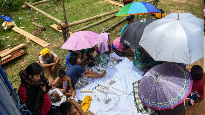Sejumlah pengungsi bencana banjir bandang dan longsor mengisi daya ponselnya di area pengungsian di Kelurahan Hutanabolon, Kecamatan Tukka,Tapanuli Tengah, Sumatera Utara, Minggu (8/12/2025). [ANTARA FOTO/Muhammad Adimaja/nz]
