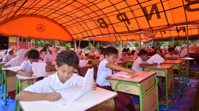 Sejumlah siswa mengikuti ujian di bawah tenda, di SDN 05 Batang Anai, Padang Pariaman, Sumatera Barat, Senin (8/12/2025). [ANTARA FOTO/Iggoy el Fitra/foc]