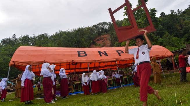 Sejumlah siswa membantu memindahkan meja dan kursi sebelum mengikuti ujian di bawah tenda, di SDN 05 Batang Anai, Padang Pariaman, Sumatera Barat, Senin (8/12/2025). [ANTARA FOTO/Iggoy el Fitra/foc]