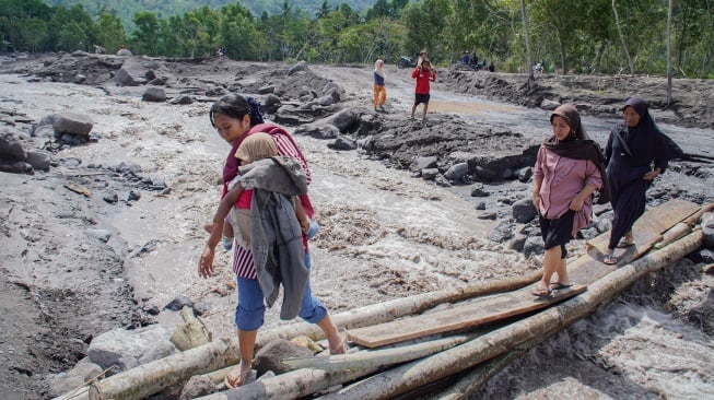 Warga melintasi jembatan darurat menuju tempat yang lebih tinggi untuk evakuasi diri di Dusun Sumberlangsep, Desa Jugosari, Kecamatan Candipuro, Lumajang, Jawa Timur, Senin (8/12/2025). [ANTARA FOTO/Irfan Sumanjaya/nz]