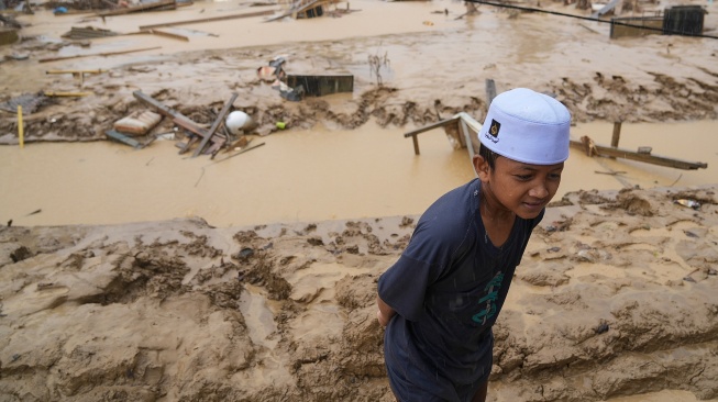 WSeorang bocah berjalan di desa yang luluh lantak pascabanjir di Desa Bundar, Karang Baru, Kabupaten Aceh Tamiang, Aceh, Selasa (9/12/2025). [ANTARA FOTO/Erlangga Bregas Prakoso/mrh/foc]