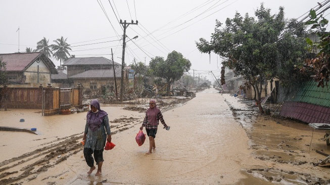 Warga berjalan di desa yang luluh lantak pascabanjir di Desa Bundar, Karang Baru, Kabupaten Aceh Tamiang, Aceh, Selasa (9/12/2025). [ANTARA FOTO/Erlangga Bregas Prakoso/mrh/foc]