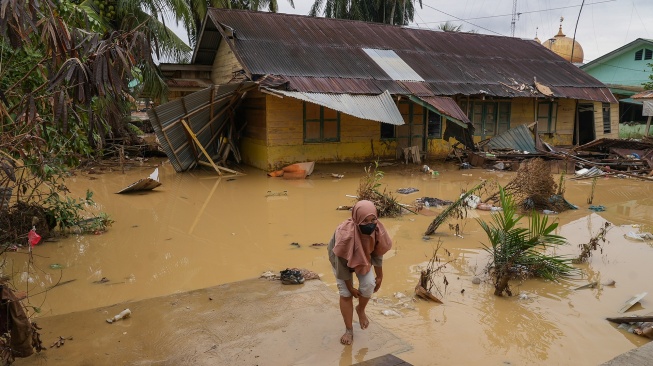 Seorang warga berjalan di depan rumah yang luluh lantak pascabanjir di Desa Bundar, Karang Baru, Kabupaten Aceh Tamiang, Aceh, Selasa (9/12/2025). [ANTARA FOTO/Erlangga Bregas Prakoso/mrh/foc]