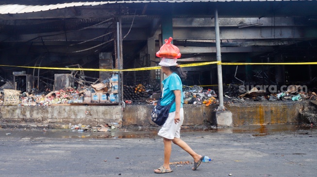 Pedagang melihat puing-puing sisa kebakaran di Pasar Induk Kramat Jati, Jakarta, Senin (15/12/2025). [Suara.com/Alfian Winanto]