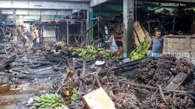 Pedagang melihat puing-puing sisa kebakaran di Pasar Induk Kramat Jati, Jakarta, Senin (15/12/2025). [Suara.com/Alfian Winanto]