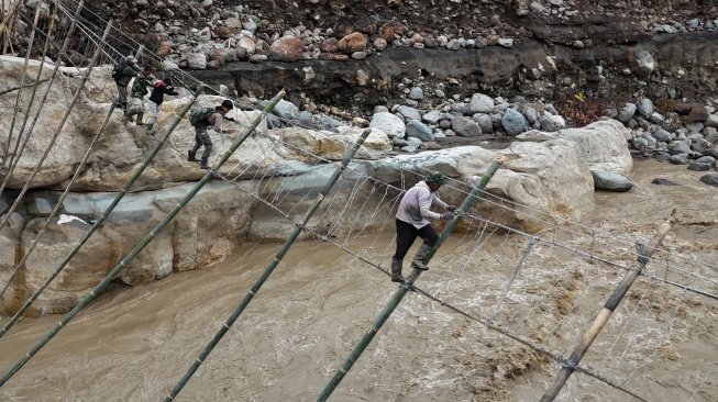 Sejumlah warga korban bencana yang terisolir melintasi Daerah Aliran Sungai (DAS) lewat jembatan tali darurat penghubung dari Desa Bergang Kecamatan Ketol, Aceh Tengah dan Desa Simpang Rahmat, Gajah Putih, Bener Meriah, Aceh, Minggu (14/12/2025). [ANTARA FOTO/Syifa Yulinnas/nz]