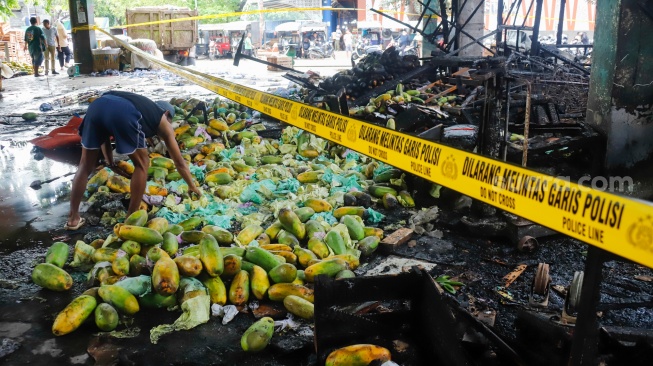 Pedagang memilih buah yang tersisa usai kebakaran di Pasar Induk Kramat Jati, Jakarta, Senin (15/12/2025). [Suara.com/Alfian Winanto]