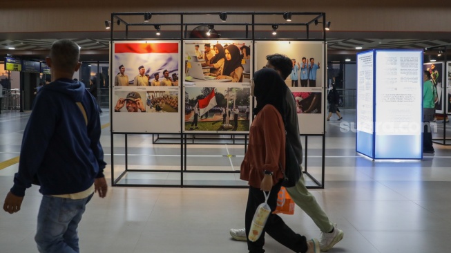 Calon penumpang melihat sejumlah karya pada pameran Haluan Merah Putih di Stasiun Tanah Abang, Jakarta, Senin (15/12/2025). [Suara.com/Alfian Winanto]