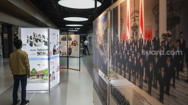 Calon penumpang melihat sejumlah karya pada pameran Haluan Merah Putih di Stasiun Tanah Abang, Jakarta, Senin (15/12/2025). [Suara.com/Alfian Winanto]
