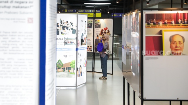 Calon penumpang melihat sejumlah karya pada pameran Haluan Merah Putih di Stasiun Tanah Abang, Jakarta, Senin (15/12/2025). [Suara.com/Alfian Winanto]