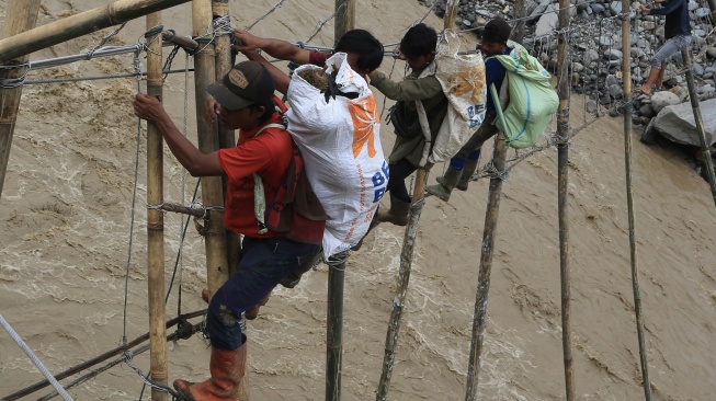 Sejumlah warga korban bencana yang terisolir melintasi Daerah Aliran Sungai (DAS) lewat jembatan tali darurat penghubung dari Desa Bergang Kecamatan Ketol, Aceh Tengah dan Desa Simpang Rahmat, Gajah Putih, Bener Meriah, Aceh, Minggu (14/12/2025). [ANTARA FOTO/Syifa Yulinnas/nz]