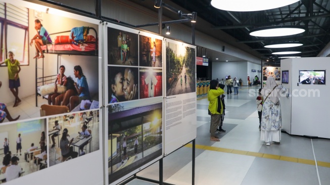 Calon penumpang melintas di dekat sejumlah karya pada pameran Haluan Merah Putih di Stasiun Tanah Abang, Jakarta, Senin (15/12/2025). [Suara.com/Alfian Winanto]
