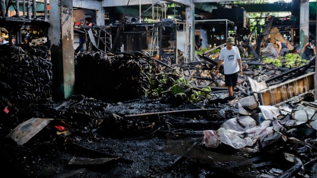 Pedagang melihat puing-puing sisa kebakaran di Pasar Induk Kramat Jati, Jakarta, Senin (15/12/2025). [Suara.com/Alfian Winanto]