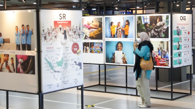 Calon penumpang melihat sejumlah karya pada pameran Haluan Merah Putih di Stasiun Tanah Abang, Jakarta, Senin (15/12/2025). [Suara.com/Alfian Winanto]