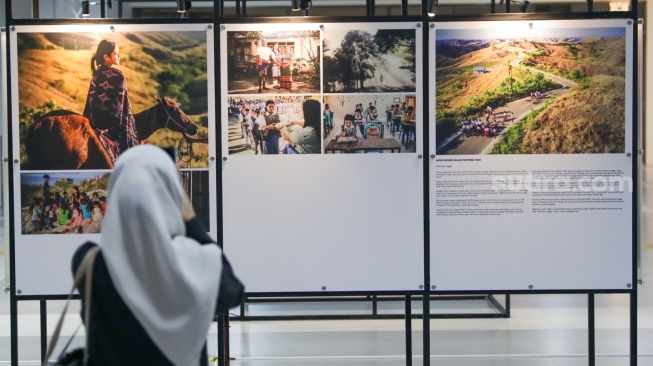Calon penumpang melihat sejumlah karya pada pameran Haluan Merah Putih di Stasiun Tanah Abang, Jakarta, Senin (15/12/2025). [Suara.com/Alfian Winanto]